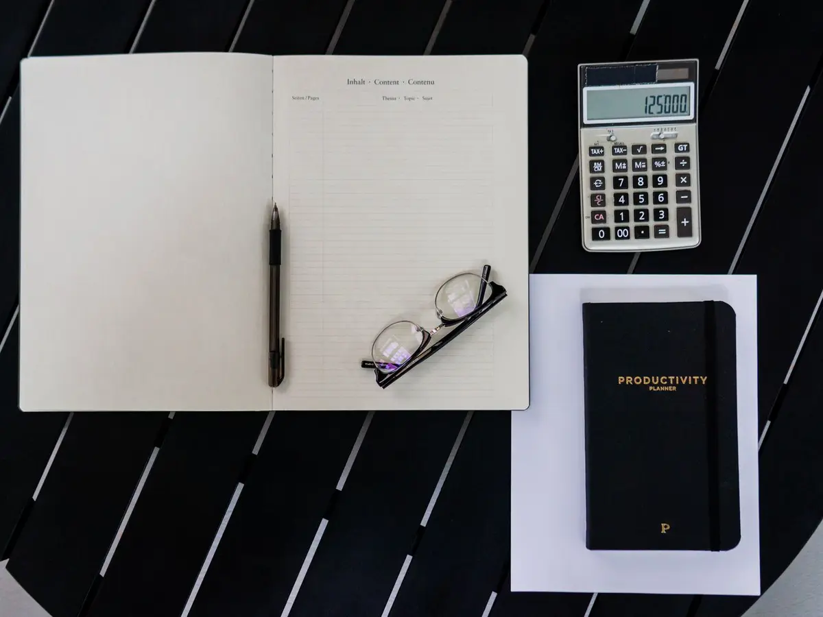 Notitieboek, rekenmachine en bril op een tafel