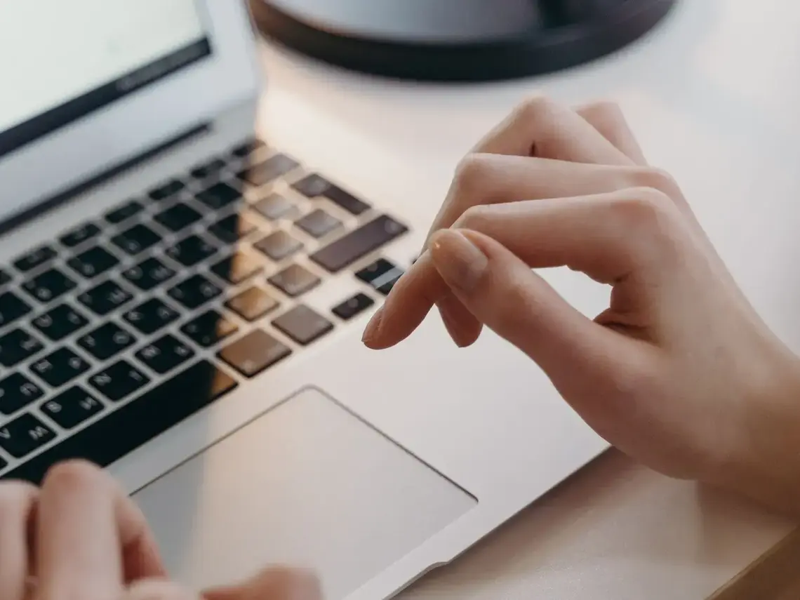Handen op het toetsenbord van een laptop aan een licht bureau