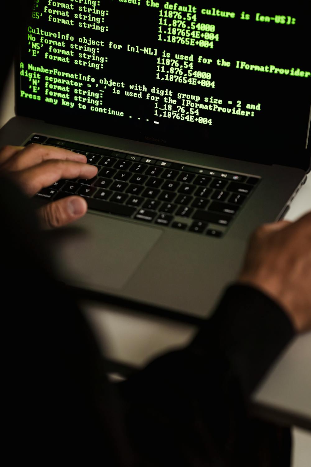 Handen typen code op een laptop in een donkere ruimte, symbool voor WordPress-beveiliging en kwetsbaarheden