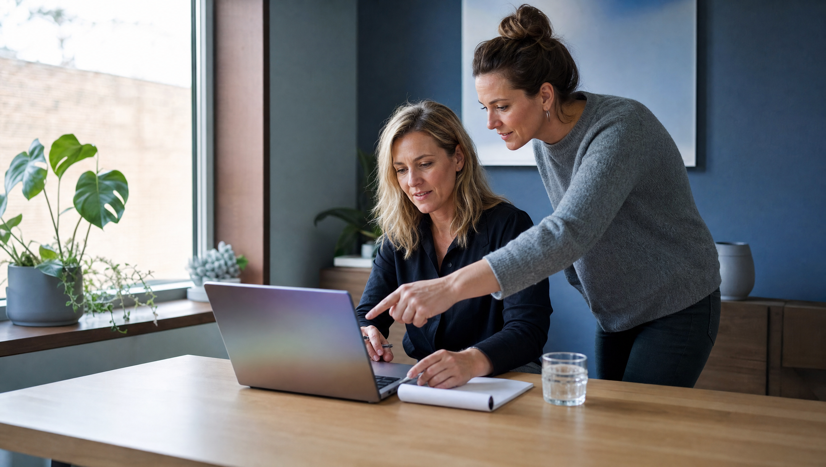 Ondernemer en collega vergelijken aan een bureau met laptop en notitieblok welk Microsoft 365-pakket bij hun bedrijf past