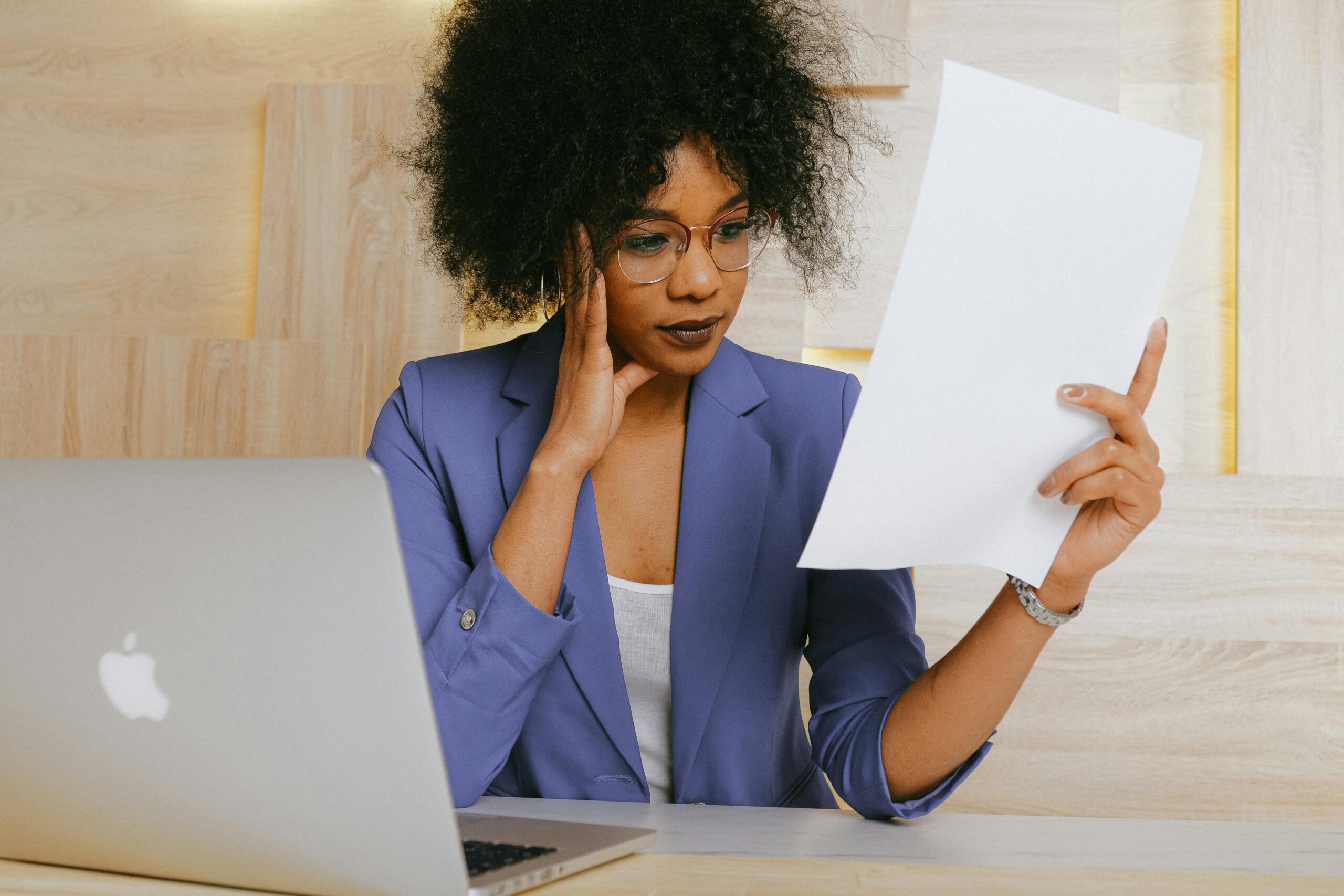 Onderneemster bekijkt geprinte documenten naast haar laptop, symbool voor de AVG-checklist die MKB-ondernemers met een WordPress website moeten doorlopen in 2026