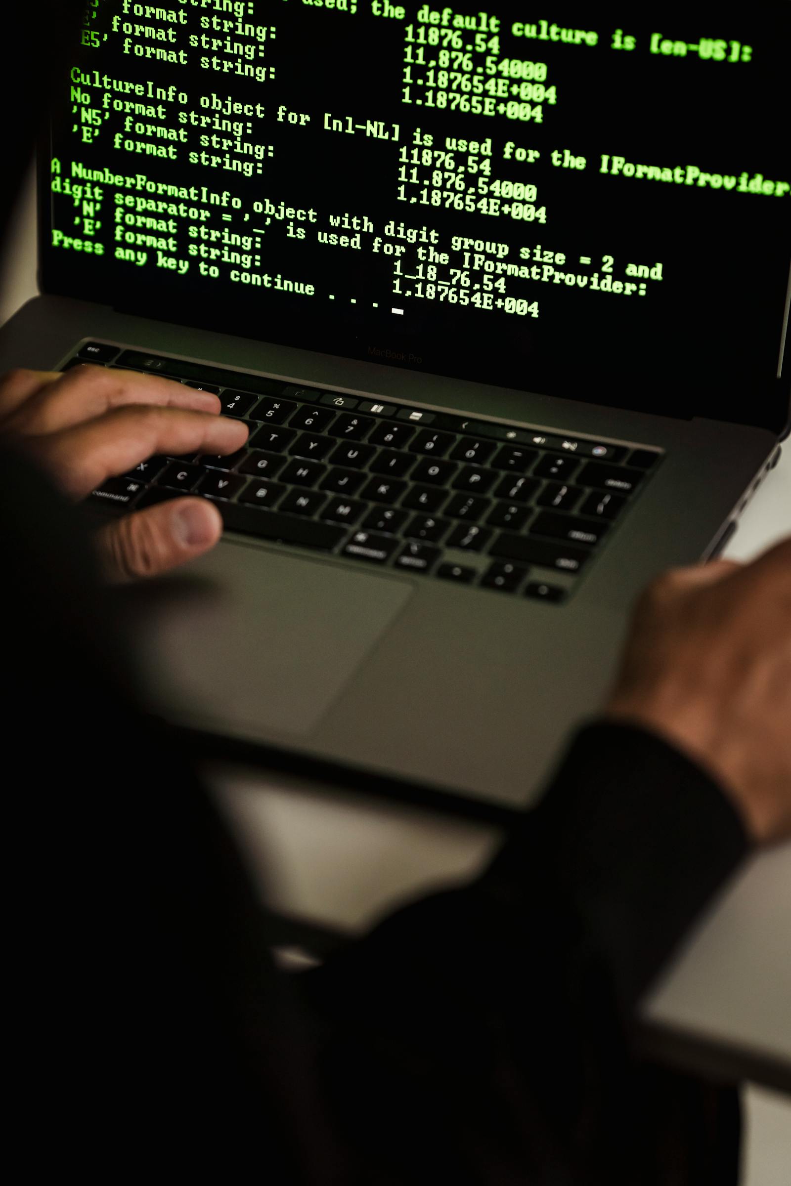 Handen typen op een laptop met code op het scherm: WordPress site gehackt noodprotocol voor het eerste uur