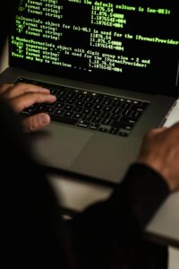 Handen typen op een laptop met code op het scherm: WordPress site gehackt noodprotocol voor het eerste uur